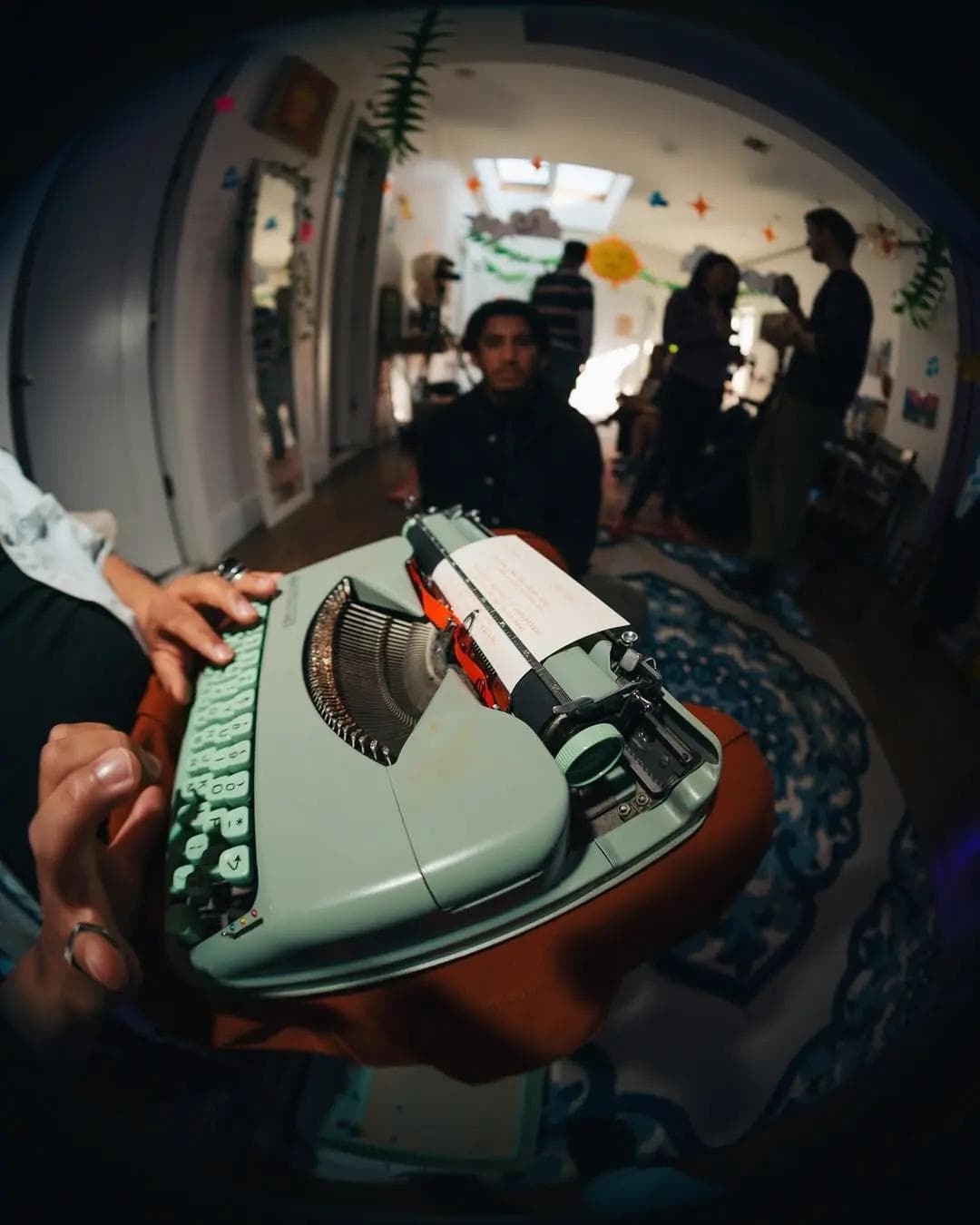 Close-up of a vintage green typewriter being used at a lively indoor gathering.